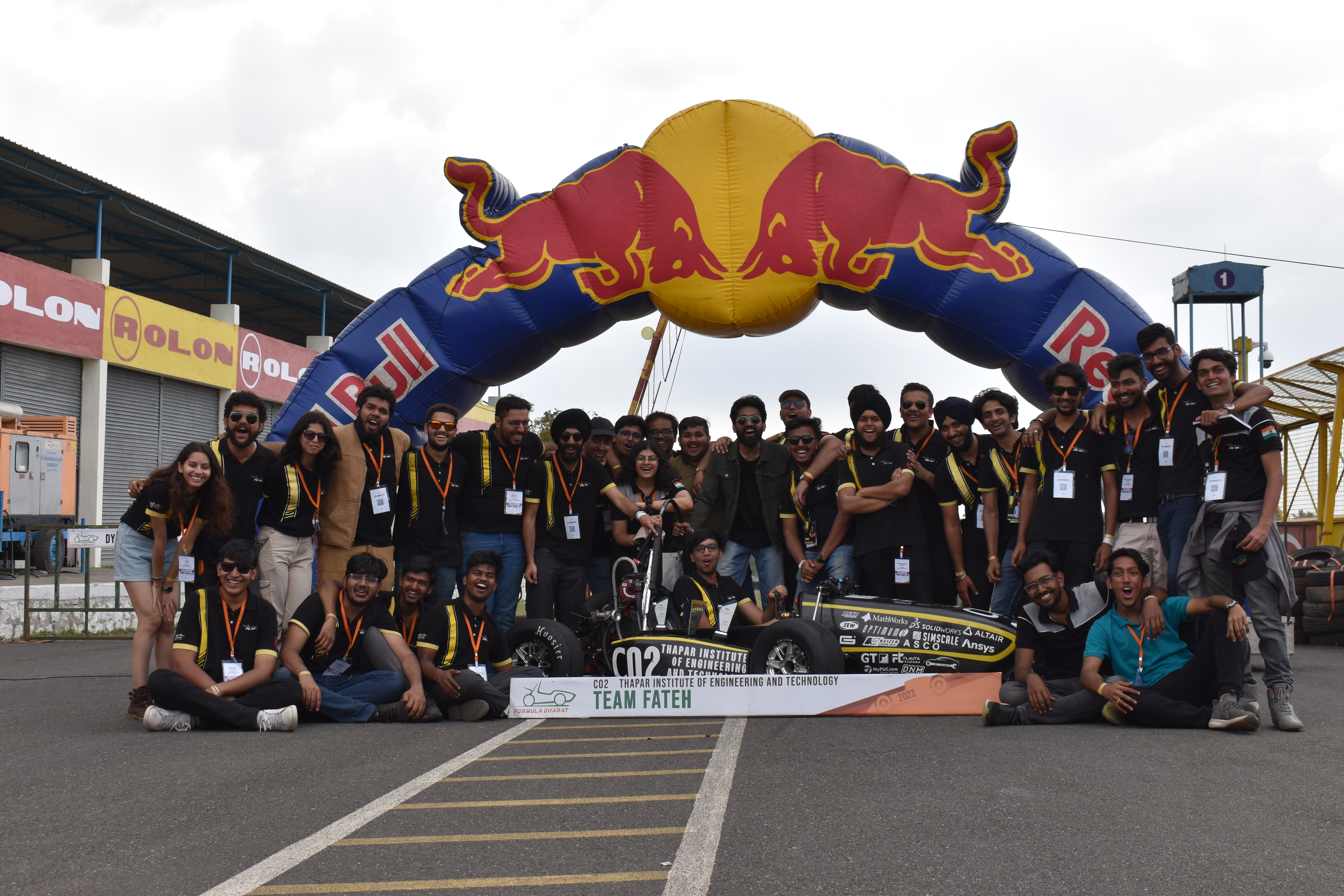 The full Team Fateh squad gathered around the car under the Red Bull arch